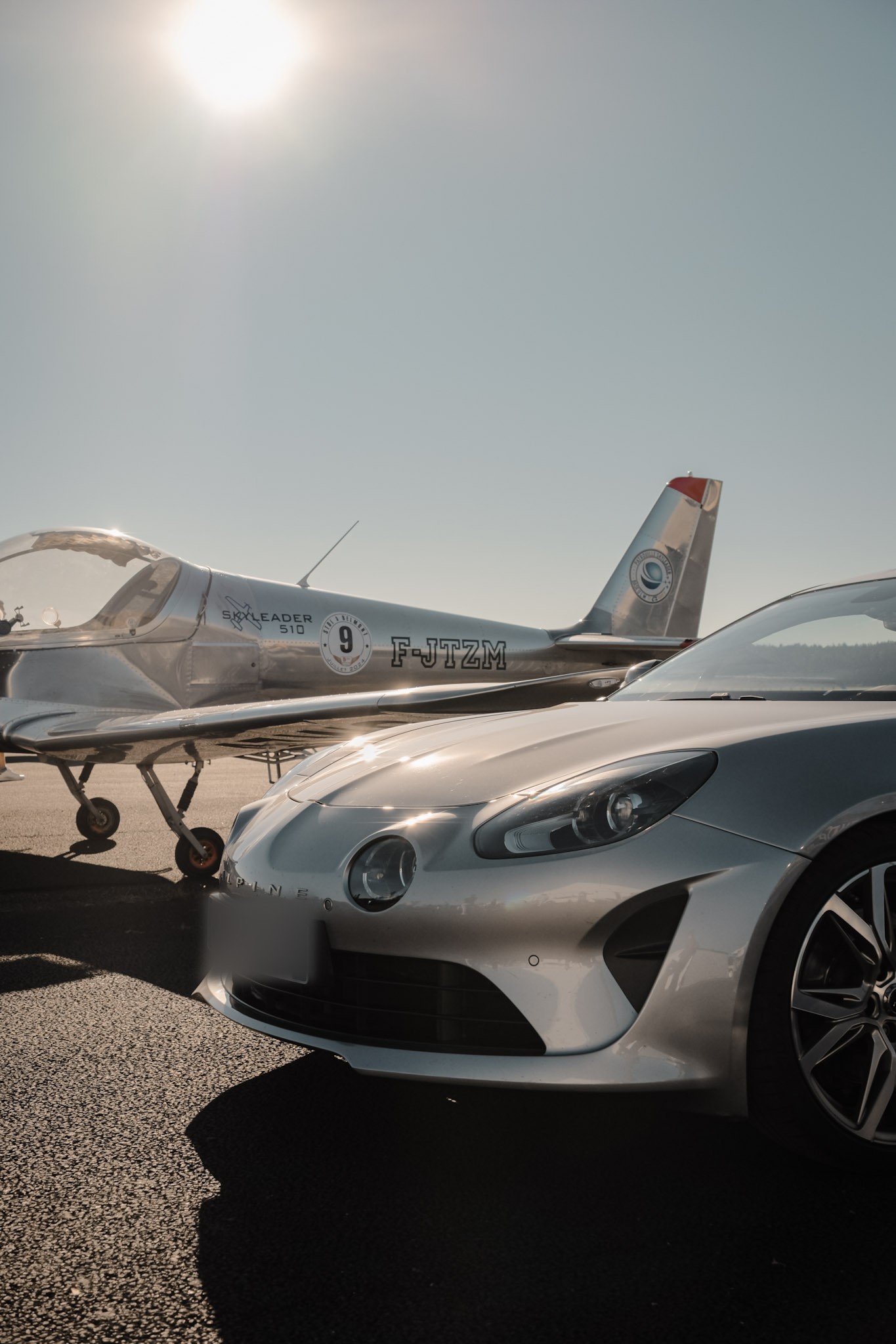 Alpine et avion à hélice sur un aérodrome, à contre-jour