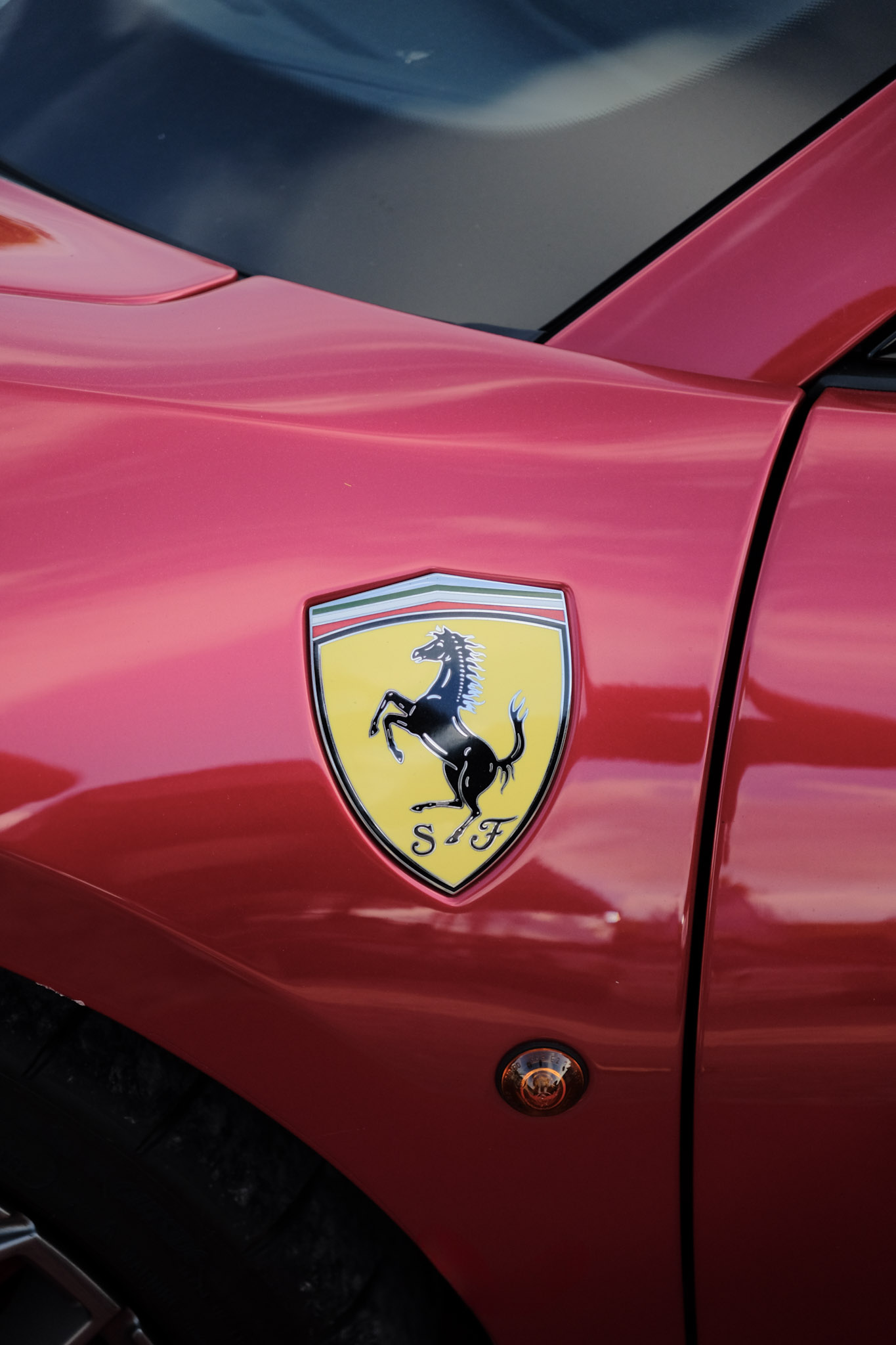 Bouclier Scuderia Ferrari sur aile rouge — cheval cabré noir sur fond jaune, lettres SF en bas