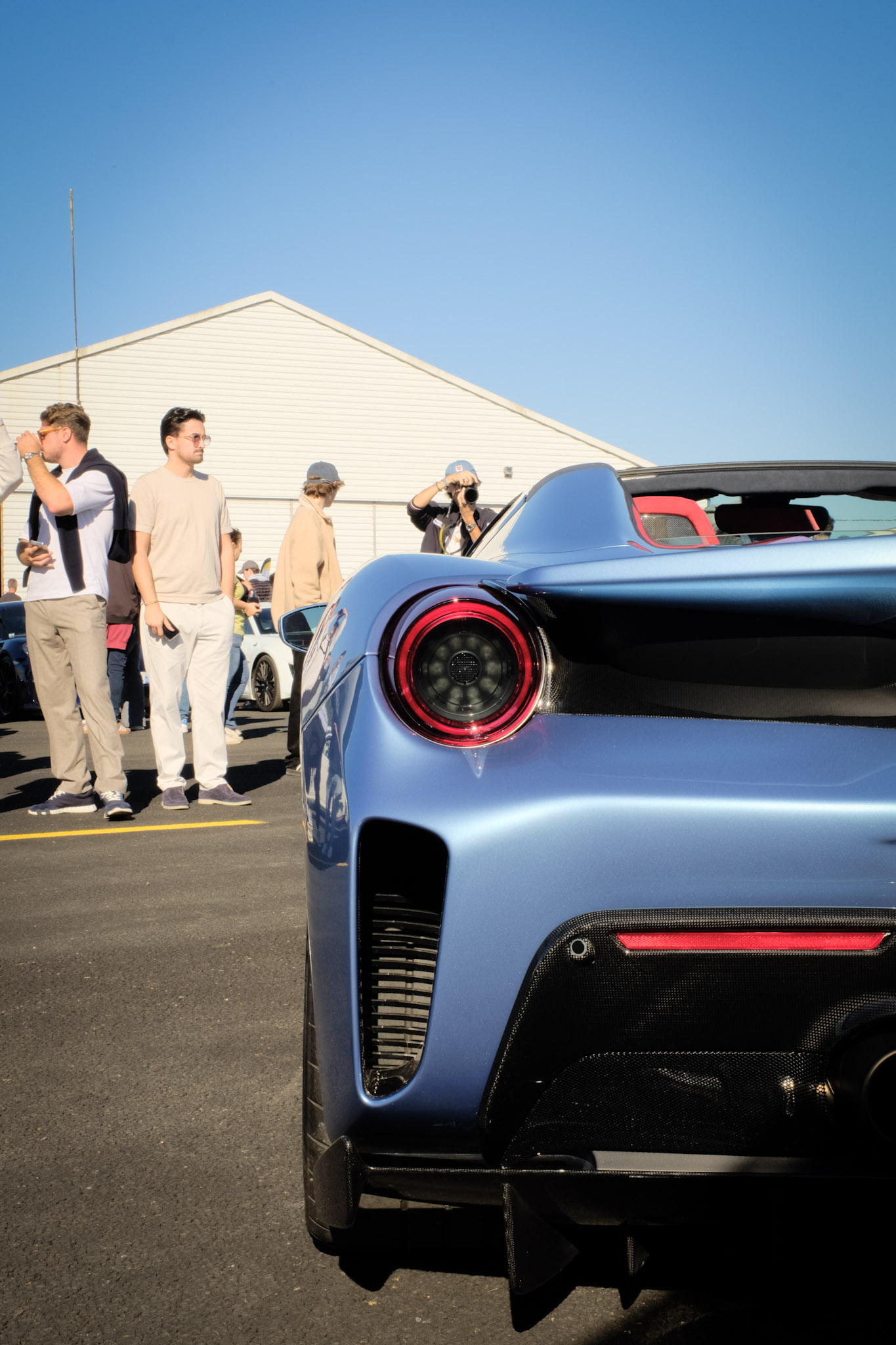 Arrière Ferrari 488 Pista Spider bleue — feu circulaire LED rouge, diffuseur carbone, foule en arrière-plan
